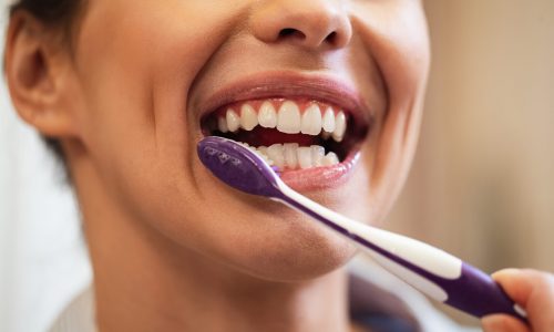 closeup-woman-using-toothbrush-while-brushing-teeth-bathroom.jpg
