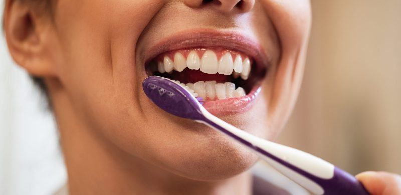 closeup-woman-using-toothbrush-while-brushing-teeth-bathroom.jpg